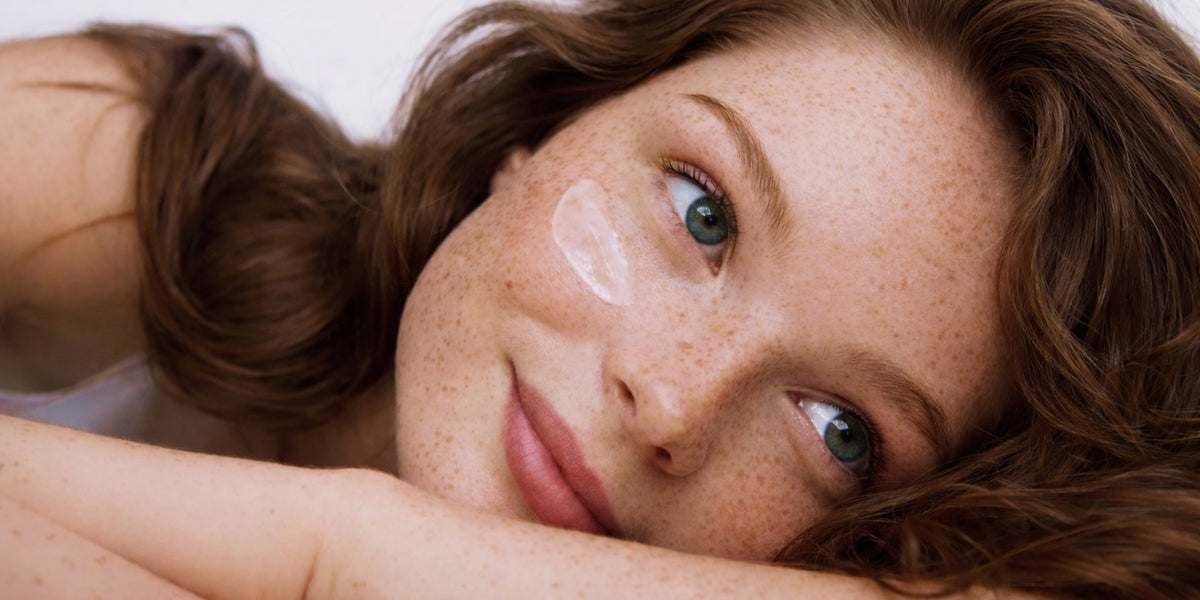 Femme souriante après l’application d’une crème hydratante pour peau sèche et déshydratée.